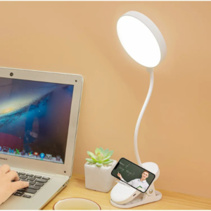 Lampe LED à pince éclairant un poste de travail avec un ordinateur portable.