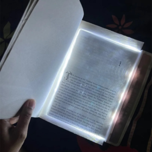 Lampe de lecture LED posée sur un livre, offrant un éclairage uniforme pour lire dans l'obscurité.