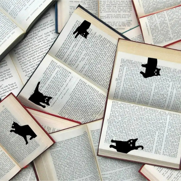 Marque-page magnétique chat noir accroché sur un livre avec une composition florale