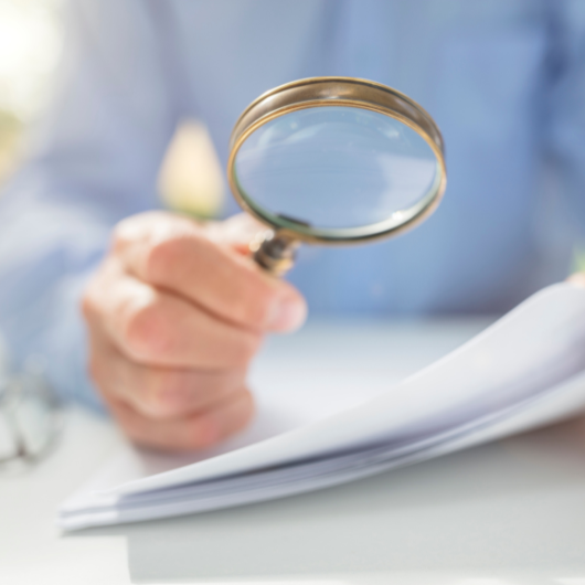 Un homme utilisant une loupe pour lire un document.