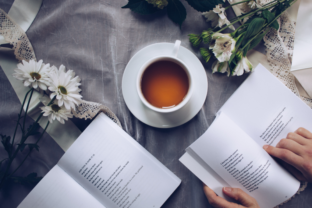 Livre ouvert accompagné d’une tasse de thé et de fleurs, une mise en scène propice à la concentration et à la rédaction d’une fiche de lecture.