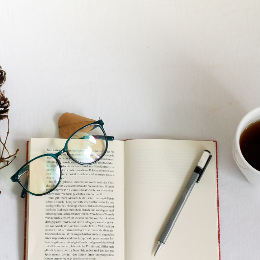 Livre ouvert avec des lunettes et un stylo, parfait pour structurer un carnet de lecture.