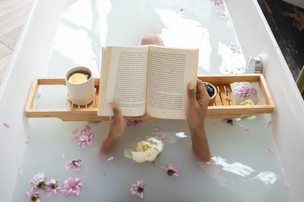 Personne lisant un livre dans un bain avec une boisson chaude, un moment propice à la réflexion pour rédiger une fiche de lecture.