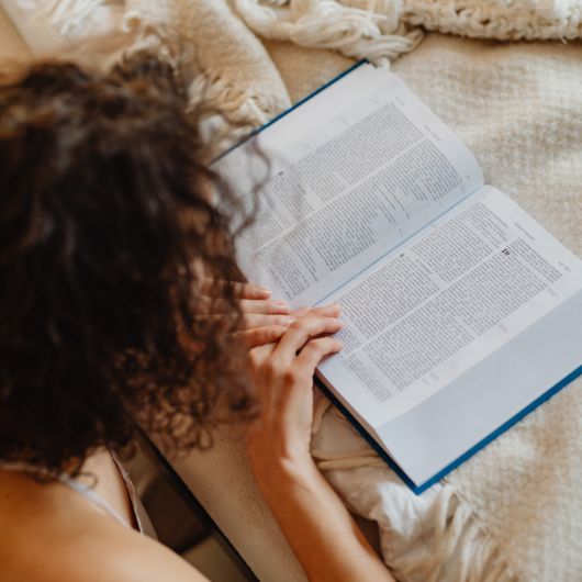 Femme prenant des notes dans un livre, un excellent moyen d'alimenter son carnet de lecture.