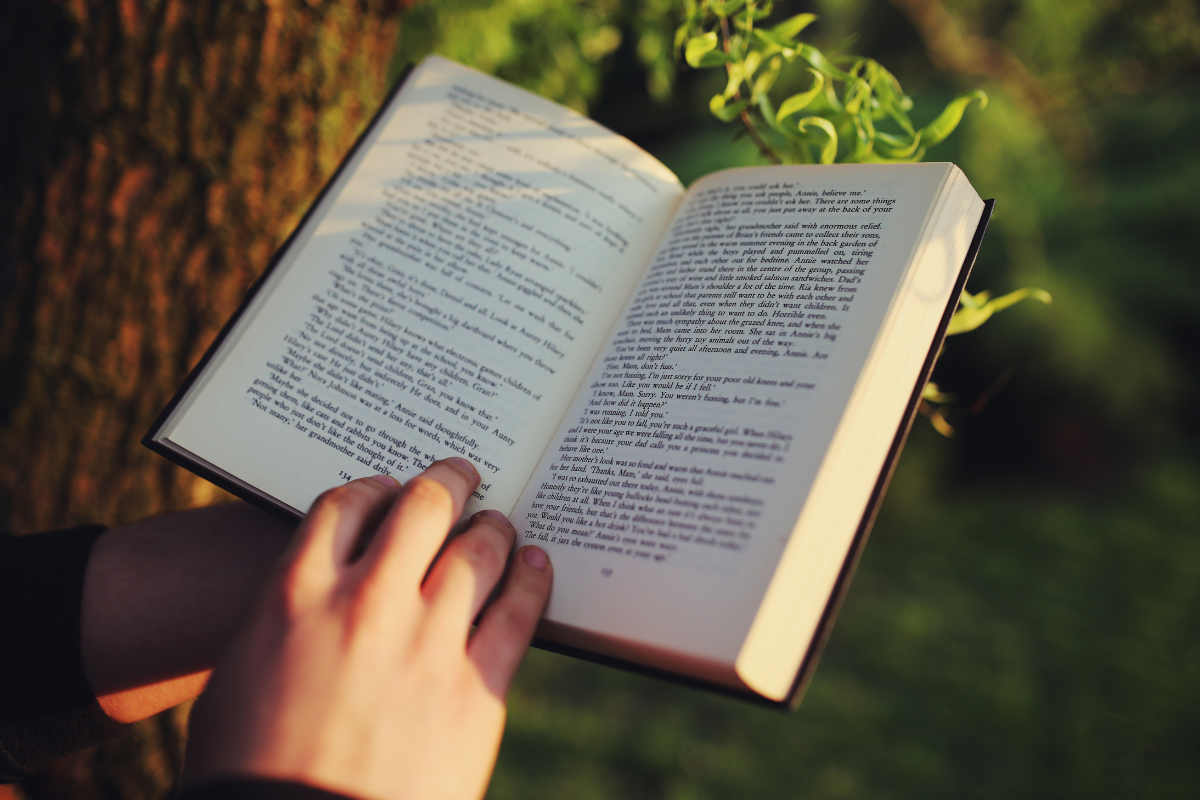 Livre ouvert accompagné d’une tasse de thé et de fleurs, une mise en scène propice à la concentration et à la rédaction d’une fiche de lecture.