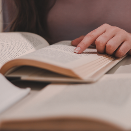 Combien de temps de lecture par jour ? 3 Femme suivant du doigt un texte dans un livre, représentant le temps de lecture journalier recommandé