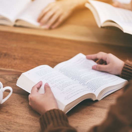 Comment faire une fiche de lecture d’un livre ? 4 Gros plan sur une personne en train de lire un livre, illustrant l’analyse personnelle pour une fiche de lecture.