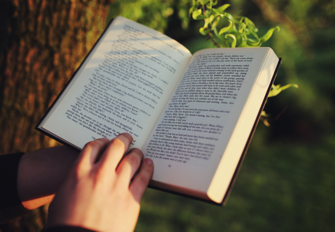 Livre ouvert accompagné d’une tasse de thé et de fleurs, une mise en scène propice à la concentration et à la rédaction d’une fiche de lecture.