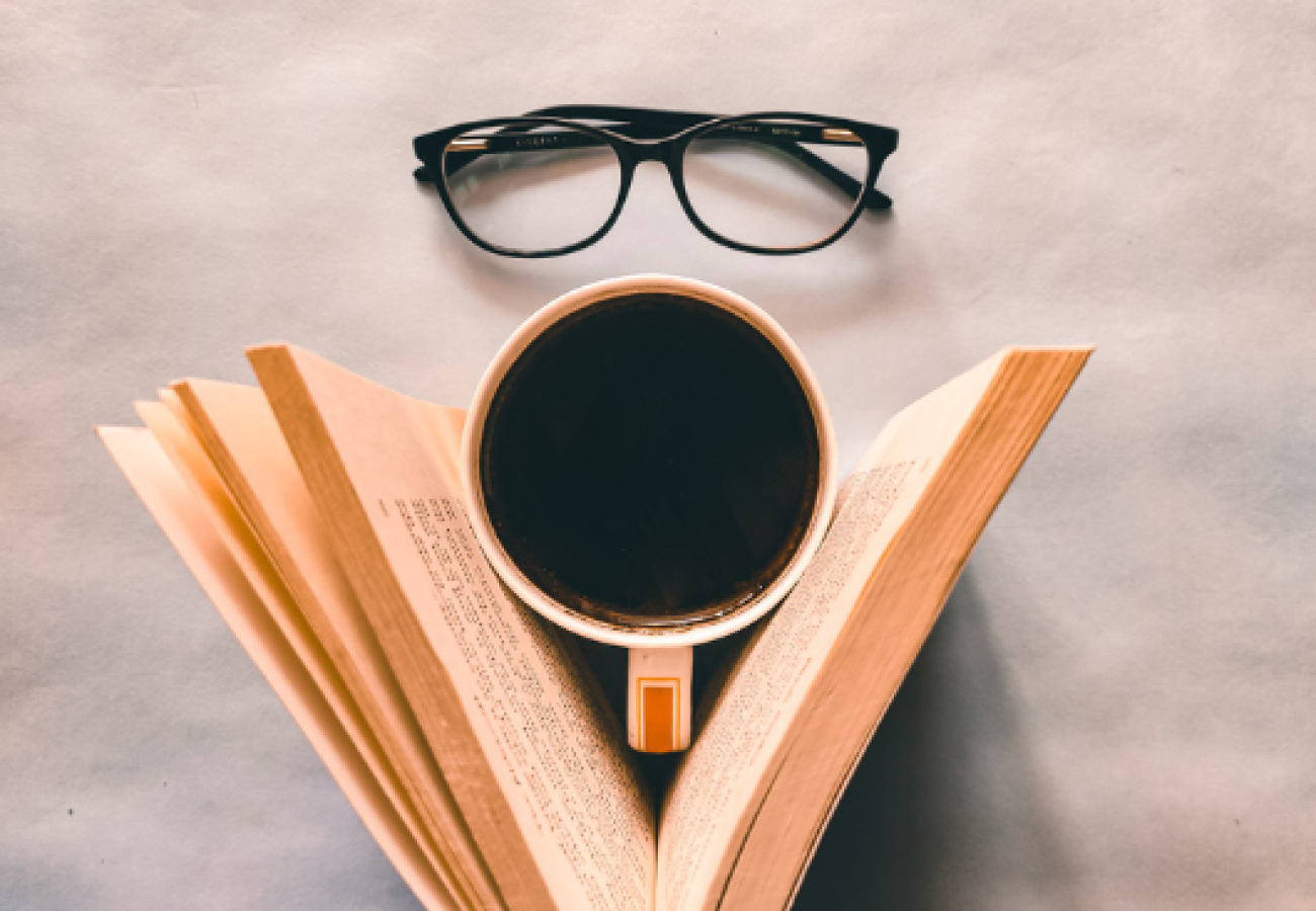 ivre ouvert avec une tasse de café et des lunettes pour illustrer une habitude de lecture quotidienne
